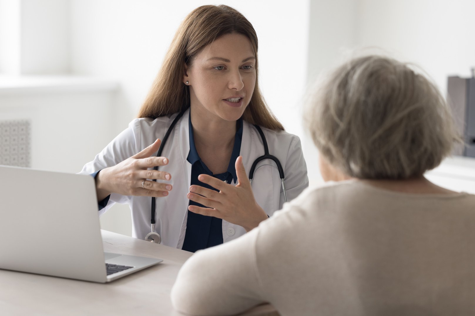 Positive geriatrician doctor woman talking to elderly patient